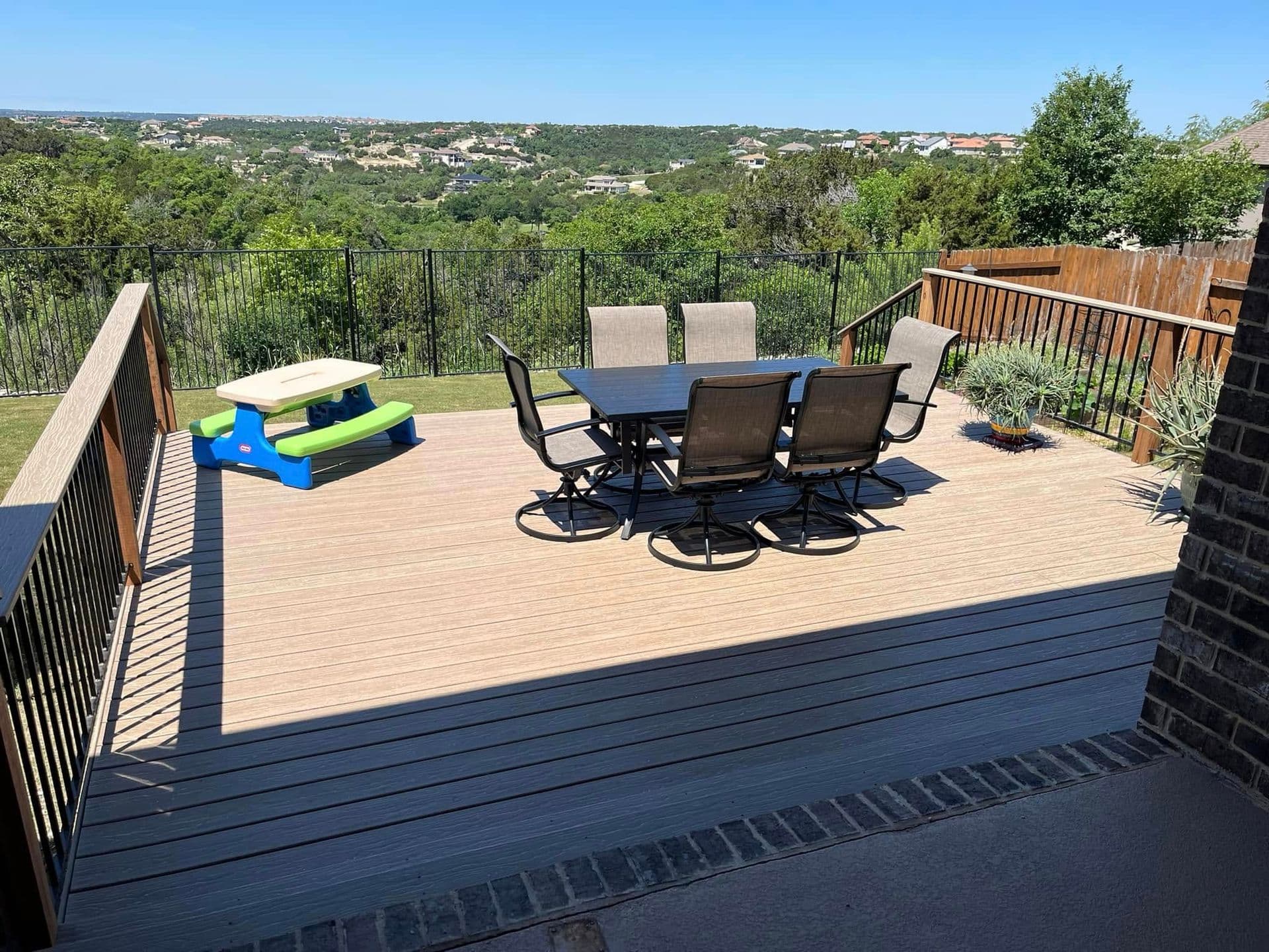 Composite deck with black metal railing and dining set overlooking Central Texas hill country